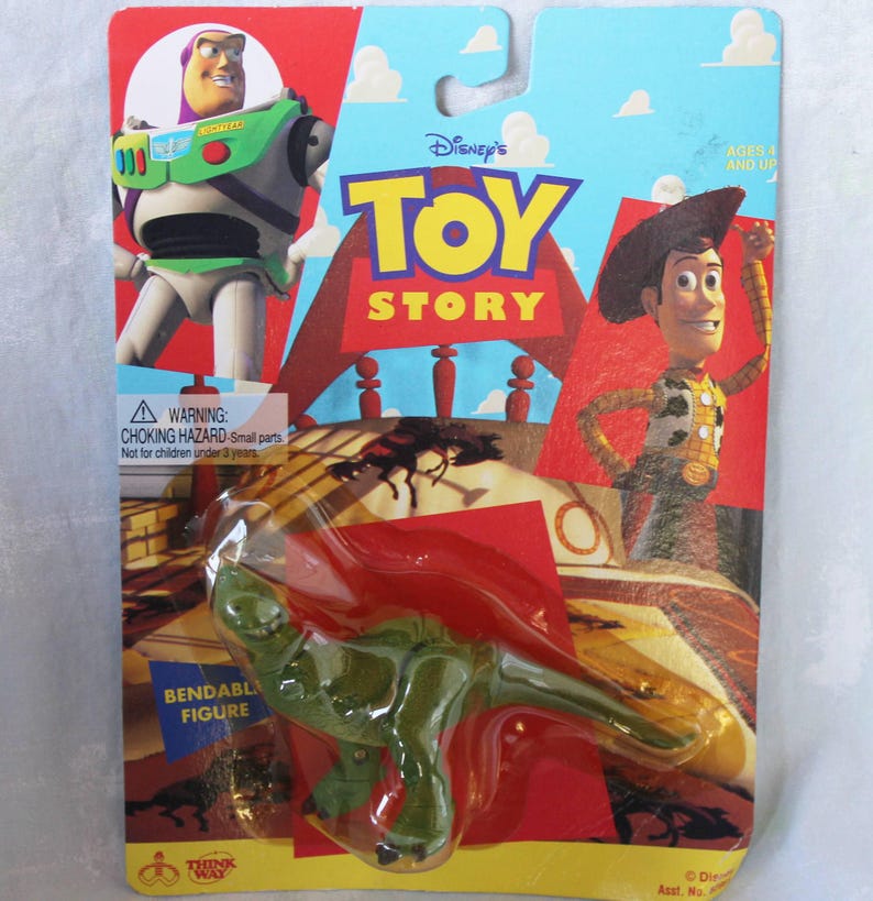 May include: A green bendable dinosaur figure in original packaging featuring Buzz Lightyear and Woody from Disney's Toy Story. The cardboard backing displays the Toy Story logo, a warning label for small parts, and the Think Way brand logo.