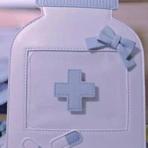 Sac bandoulière en forme de bouteille médicale – Joli sac à main pastel Nursecore avec fenêtre transparente, motif flacon de pilules et nœud pour un look cosplay tendance