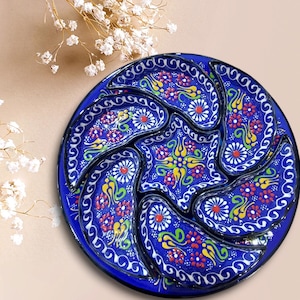 Puede incluir: Un plato de servir de cerámica azul con seis compartimentos individuales. Los compartimentos están decorados con coloridos patrones florales y acentos blancos.
