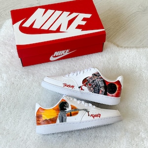 May include: White Nike trainers with custom artwork featuring a red and black design and the word "Berserk". The trainers are displayed with a red Nike box.