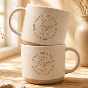 May include: Two stacked ceramic mugs with a speckled off-white finish and a brown base. Each mug features a circular emblem printed on the front containing the text "YOUR Logo HERE" in a script and sans-serif font combination.