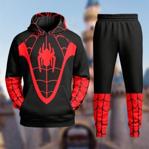 May include: A black hooded sweatshirt and matching sweatpants set featuring a red spider emblem on the chest and a red spiderweb pattern on the sleeves and lower pant legs. The hoodie includes a front kangaroo pocket and a drawstring hood.