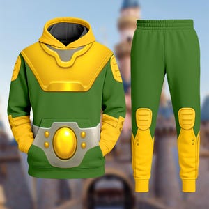 May include: Green and yellow hoodie and matching pants set. The hoodie features a yellow collar and accents, a gray belt design with a large yellow oval, and a front pocket. The pants have yellow accents on the knees and ankles. The outfit is designed with a superhero theme.
