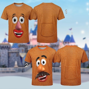 May include: Two orange t-shirts with a textured surface. One shirt features a cartoon face with large eyes, a pink nose, and a red mouth. The other shirt has a cartoon face with a mustache. Both shirts have a pocket on the back.