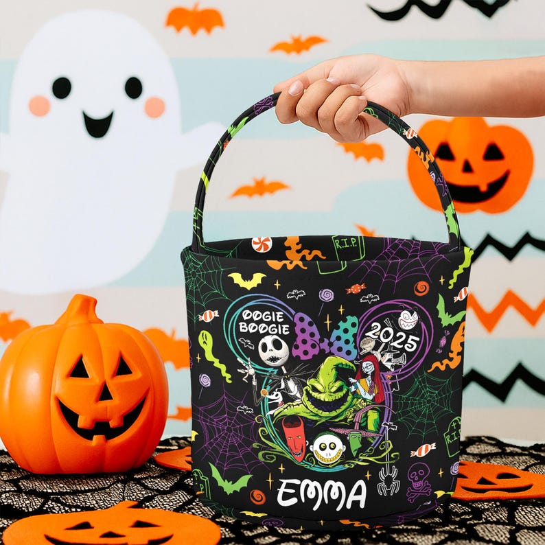 May include: Black Halloween trick-or-treat bag with a colorful design featuring characters from "The Nightmare Before Christmas." The bag has a handle and the name "EMMA" printed on it. The background includes pumpkins and bats.
