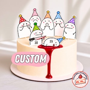 Könnte beinhalten: Ein runder Kuchen mit mehreren weißen Cartoon-Figuren als Tortenaufstecker, die bunte Partyhüte tragen. Eine Figur hält ein Messer, eine andere liegt flach mit der Zahl 29 und eine dritte trägt die Zahl 30. Roter Sirup läuft an der Seite herab.