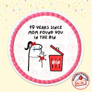 May include: A round cake with a pink frosting border and the text "19 YEARS SINCE MOM FOUND YOU IN THE BIN". The cake features a cartoon illustration of a person holding a baby near a red bin.