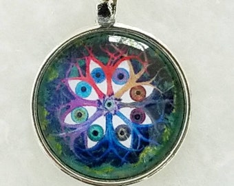 May include: A silver pendant with a round glass cabochon featuring a colorful eye mandala design. The mandala has a white center with eight eyes radiating outward, each with a different colored iris and pupil. The eyes are surrounded by a network of swirling lines in shades of blue, purple, and red.