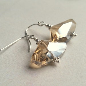May include: A pair of silver dangle earrings with clear and amber crystal teardrop shaped stones.