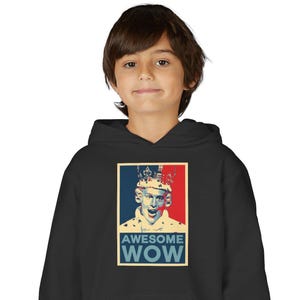 Può includere: Felpa con cappuccio nera con una grafica di una persona con una corona e le parole "AWESOME WOW" in blu, rosso e bianco. La felpa è indossata da un bambino.