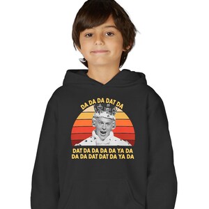 Peut inclure: Sweat à capuche noir avec un motif d'une personne couronnée sur fond de coucher de soleil. Le texte "DA DA DA DAT DA" et "DAT DA DA DA DA YA DA DA DA DAT DAT DA YA DA" est imprimé au-dessus et en dessous du motif.