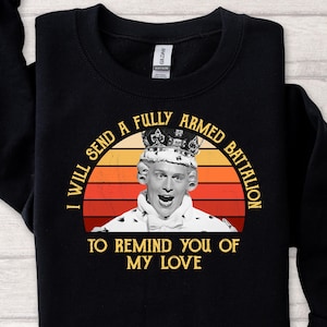 Könnte beinhalten: Schwarzes Sweatshirt mit einem Grafikdesign, das eine Person mit Krone zeigt. Der Text lautet: "I WILL SEND A FULLY ARMED BATTALION TO REMIND YOU OF MY LOVE" in einem kreisförmigen Design mit Sonnenuntergangshintergrund.
