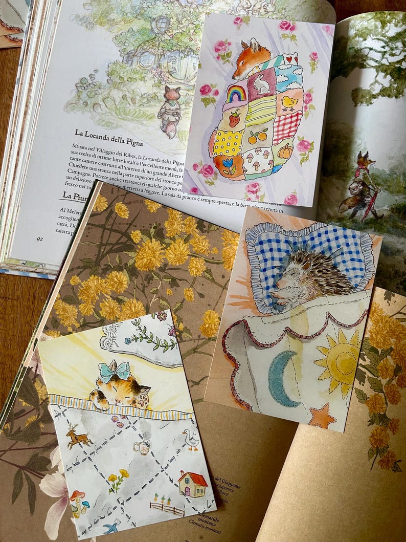 May include: Three rectangular art prints featuring watercolour illustrations of a sleeping fox under a patchwork quilt, a hedgehog resting on a blue checkered pillow, and a calico cat with a blue bow sleeping under a patterned blanket.
