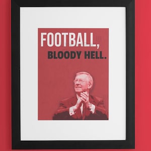 Peut inclure: Une impression encadrée avec un fond rouge et une image en noir et blanc d'un homme avec le texte "FOOTBALL, BLOODY HELL."