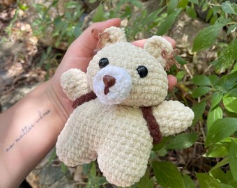 Handgemaakte gehaakte amigurumi beer – bruin en beige, met een rugzakje en kleine strikjes in zijn oren.