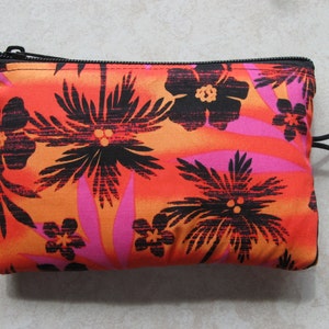 May include: A small, black zippered pouch with a tropical print. The print features black palm trees and flowers on a bright orange, pink, and red background.
