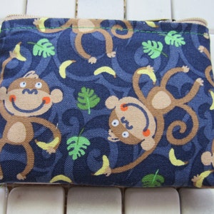 May include: A blue zippered pouch with a monkey print. The monkeys are brown with yellow bananas and green leaves.