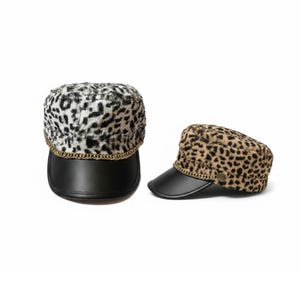 May include: Two military-style hats with a leopard print design. One hat features a black and white pattern, while the other has a tan and brown pattern. Both hats have a black brim and a gold chain detail around the base.