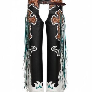 May include: Black leather chaps featuring a brown tooled leather waistband and upper thigh panels with floral cross motifs. The legs are accented with white leather overlays, turquoise trim, and long white and metallic teal fringe along the sides.