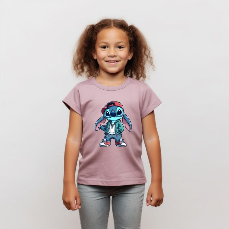 May include: A young girl wearing a mauve t-shirt with a blue cartoon character wearing a red hat, green jacket, and jeans. The character is holding a microphone and has a silver chain around its neck.