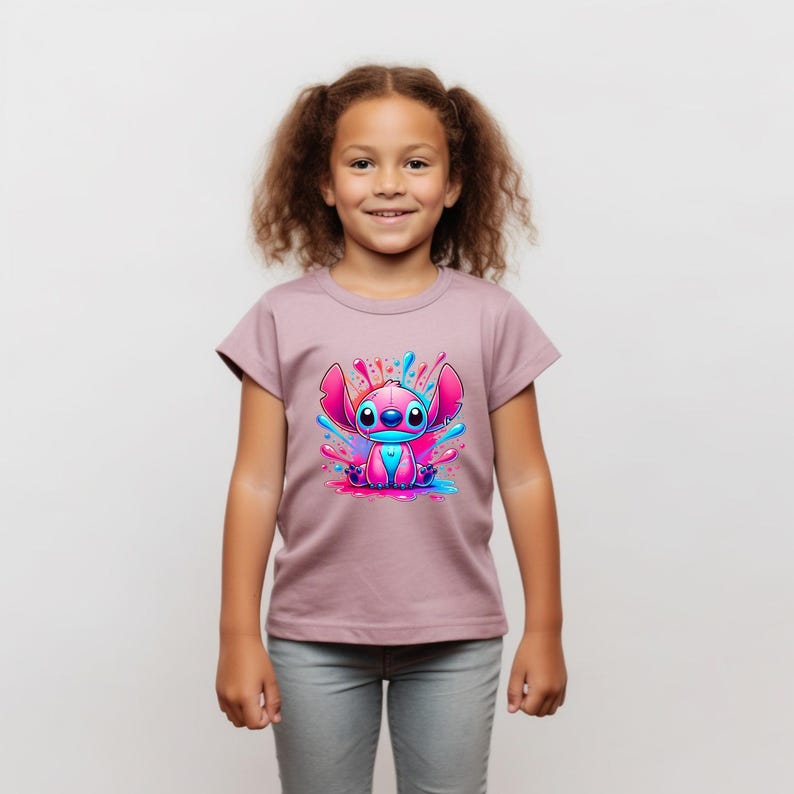 May include: A pink t-shirt featuring a cartoon blue and pink Stitch character in a colourful paint splatter design.