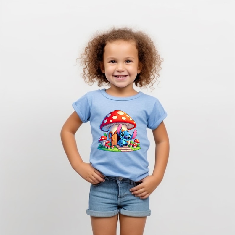 May include: A light blue t-shirt with a cartoon image of Stitch from Lilo & Stitch standing in front of a red and white mushroom house.