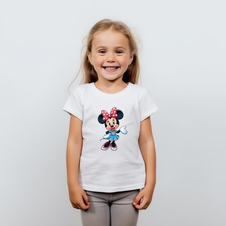 May include: White t-shirt with a cartoon image of Minnie Mouse wearing a red bow and a blue polka dot dress.