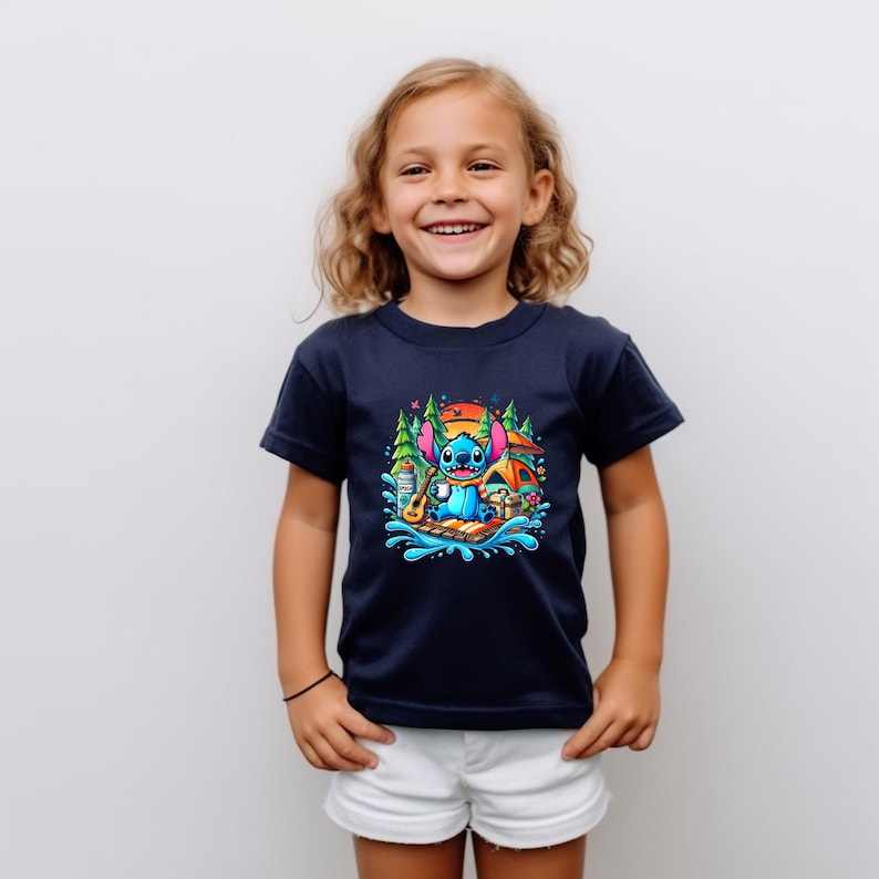 Puede incluir: Una camiseta azul marino con un gr&aacute;fico colorido de Stitch de Lilo & Stitch. El dise&ntilde;o muestra a Stitch con un ukelele, acampando cerca de una tienda de campa&ntilde;a y &aacute;rboles. La camiseta la lleva un ni&ntilde;o peque&ntilde;o.