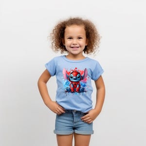 May include: A young child wearing a light blue t-shirt with a colorful graphic of Stitch dressed as Spiderman. The graphic has blue, red, and white paint splatters.
