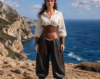 May include: A cream-colored long-sleeved shirt with a collar, a brown leather corset with a belt, dark charcoal loose-fitting trousers, brown leather wrist cuffs, a brown headscarf, and dark brown boots with buckles and straps.