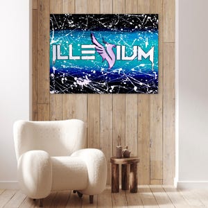 Op de afbeelding: Een ingelijst kunstwerk met het woord "ILLENIUM" in witte letters, een roze vleugelontwerp en een achtergrond van blauwe en zwarte verfspetters. Het kunstwerk hangt aan een houten muur boven een witte fauteuil.