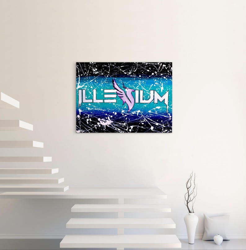 Op de afbeelding: Een canvas kunstwerk met het woord "ILLENIUM" in witte blokletters, een paars vleugelontwerp en een blauw-zwarte achtergrond met witte verfspatten. Het kunstwerk wordt aan een witte muur getoond.
