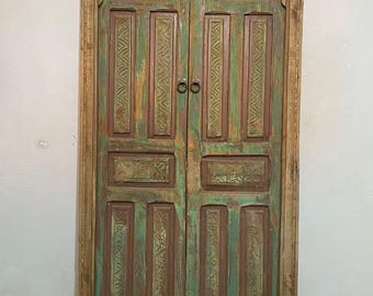 Pode incluir: Portas duplas de madeira antigas com acabamento envelhecido. As portas são pintadas em tons de verde e castanho, com detalhes entalhados intrincados. A moldura é de cor de madeira natural e as portas têm pequenas maçanetas redondas de metal. As portas têm cerca de 180 cm de altura.
