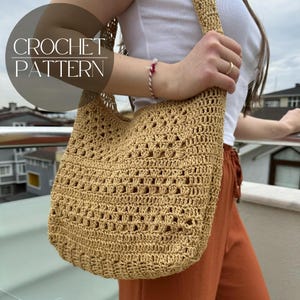 Op de afbeelding: Een gehaakte beige tote bag met een vierkant patroon. De tas wordt over de schouder gedragen door iemand die een wit shirt en een oranje broek draagt.
