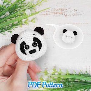 May include: A handmade white and black crochet panda pin. The panda has black ears, eye patches, and a nose. The pin is shown with a smaller version in a speech bubble. The text "PDF Pattern" is at the bottom.