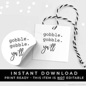 Könnte beinhalten: Ein weißer runder Aufkleber mit schwarzem Text, der "gobble. gobble. ya'll" lautet. Der Aufkleber ist teilweise abgezogen, um einen weißen Hintergrund freizulegen. Ein weißes quadratisches Etikett mit schwarzem Text, der "gobble. gobble. ya'll" lautet, ist an einer schwarz-weißen Schnur befestigt.
