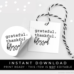 May include: A printable gift tag with the text "grateful. thankful. blessed." in black text on a white background. The tag is tied with a black and white twine.