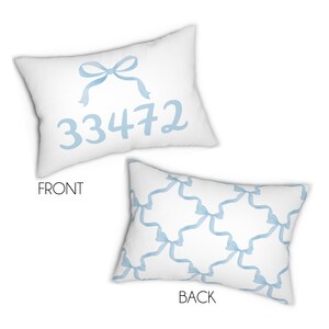 May include: A white pillow with a blue bow and the number 33472 printed on the front. The back of the pillow has a repeating pattern of blue bows.