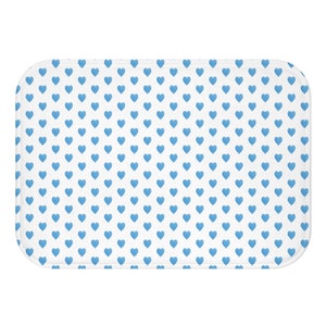 May include: A white bath mat with a repeating pattern of small blue hearts.
