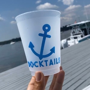 May include: A white plastic cup with a blue anchor and the text "DOCKTAILS" printed on it.