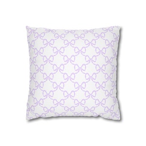 May include: A white pillow with a light purple bow pattern.