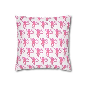 May include: A white pillow with a pink monkey pattern. The monkeys are all facing forward with their arms raised in the air.