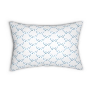 May include: A white pillow with a light blue bow pattern. The pillow is rectangular and has a soft, plush texture.