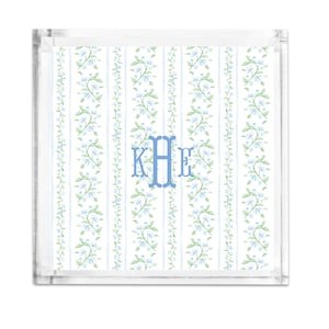 May include: A clear acrylic tray with a white background and a blue floral pattern. The tray has a monogram of the letters "KHE" in blue.