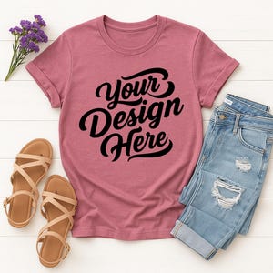 Mockup bundle featuring Gildan 64000 t-shirts in over 70+ colors. The image shows various colored t-shirts with the placeholder text 'Your Design Here' on a flat lay background with flowers, sneakers, and other accessories.
