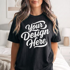 Maqueta de camiseta negra Gildan 5000 en modelo, camiseta de corte clásico en un ambiente acogedor de dormitorio, expositor de camisetas de impresión bajo demanda premium para vendedores de Etsy.