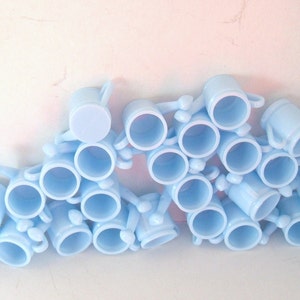 May include: A group of light blue ceramic mugs with handles. The mugs are stacked and arranged in a semi-circle.