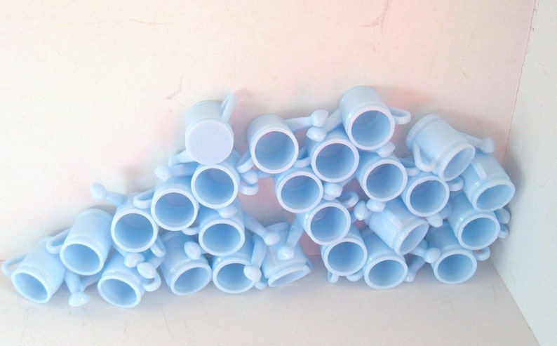 May include: A group of light blue ceramic mugs with handles. The mugs are stacked and arranged in a semi-circle.