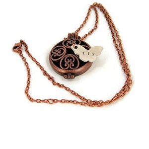 May include: A copper chain necklace with a filigree locket and a silver butterfly charm with the word "fly" inscribed on it.