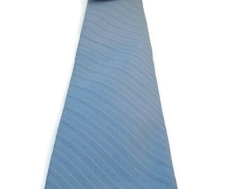 May include: A light blue tie with thin white stripes. The tie has a pointed end and is made of a smooth fabric.